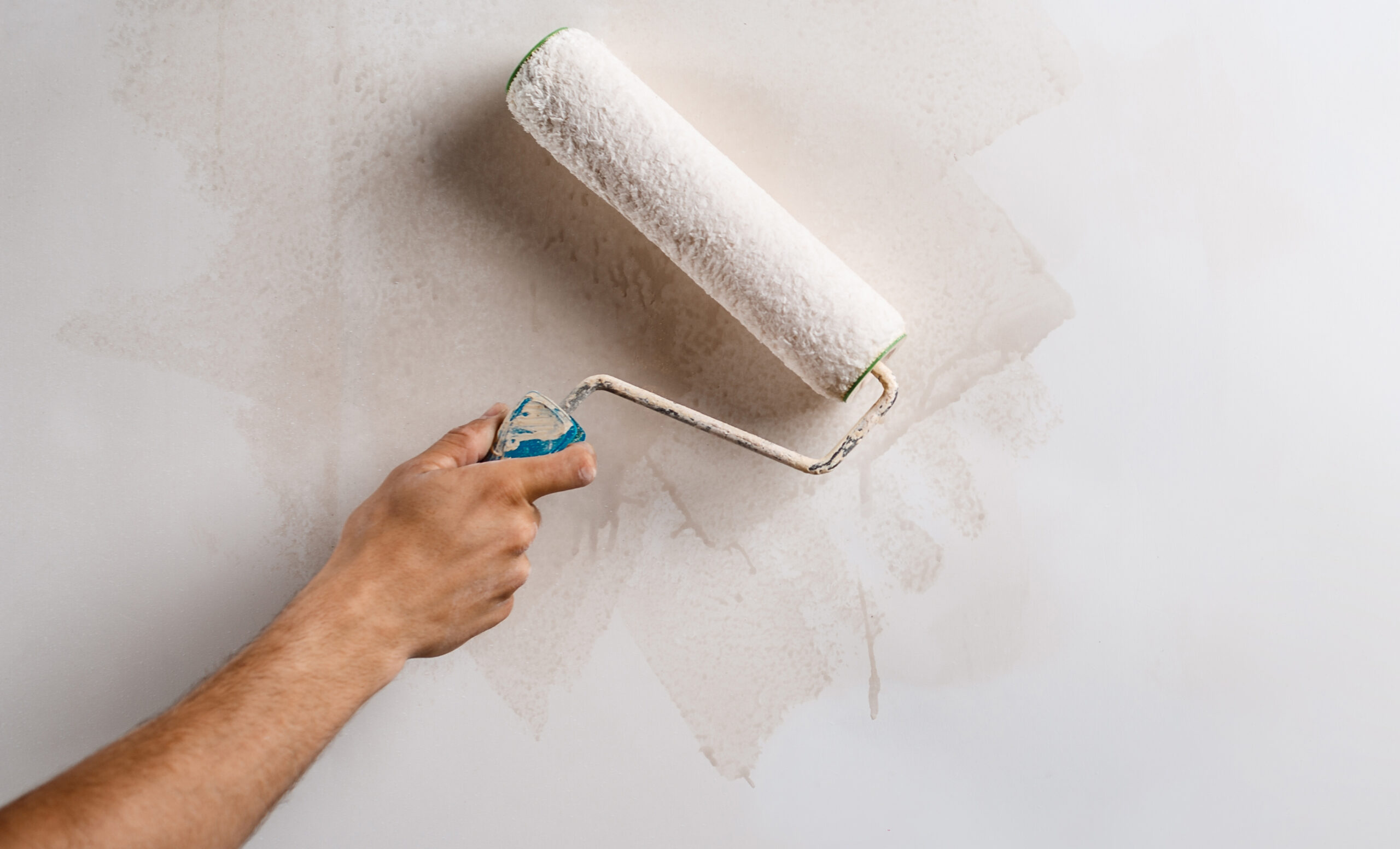 Close up photo of hand painting wall with roller in white color. Copy space.